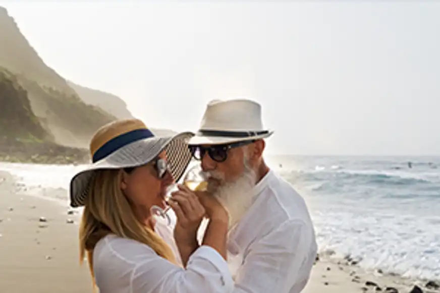 Zwei Menschen die am Strand ein Glas Wein trinken