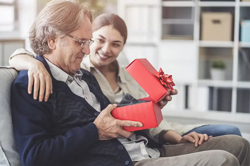 Älterer Mann öffnet Geschenk von Frau
