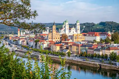Blick auf eine europäische Stadt am Fluss mit Dom und historischer Architektur.
