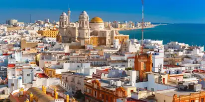 Panoramablick auf die Stadt Cádiz, Spanien, mit der Kathedrale von Cádiz im Vordergrund und dem Meer im Hintergrund.