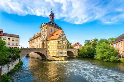 Fachwerkhaus auf Brücke über Fluss bei blauem Himmel.