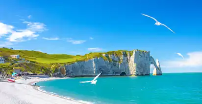 Klippen von Étretat bei sonnigem Wetter mit blauem Himmel und Möwen.