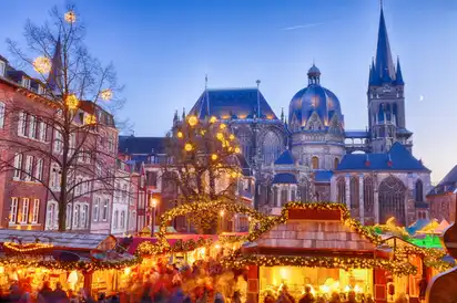 Weihnachtsmarkt mit Dom im Hintergrund bei Abenddämmerung.