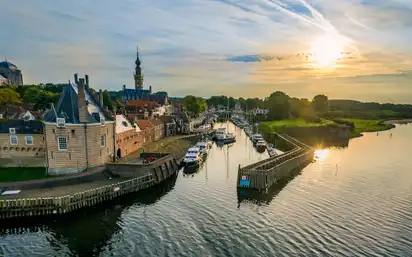 Historische Stadtansicht bei Sonnenuntergang mit Hafen und Wasserstraße.