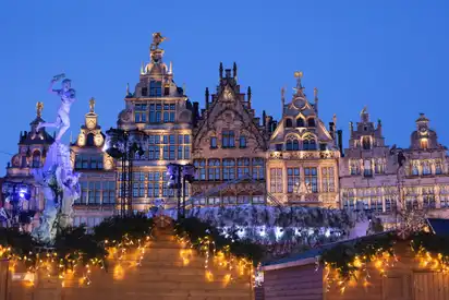 Historische Gebäude und Weihnachtsmarktlichter in Antwerpen bei Nacht.