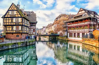 Fachwerkhäuser an einem Kanal in einer historischen Stadt bei sonnigem Wetter.