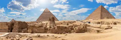 Die Sphinx und Pyramiden von Gizeh bei sonnigem Himmel.