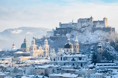 Winterlicher Blick auf die Festung Hohensalzburg und die verschneite Altstadt von Salzburg.
