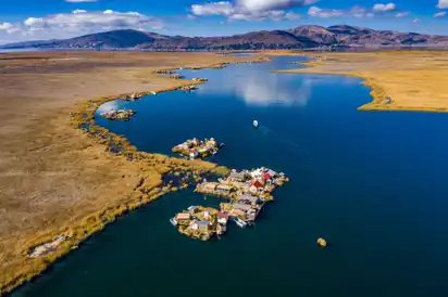 Schwimmende Inseln auf einem See mit Hütten und umliegender Landschaft.