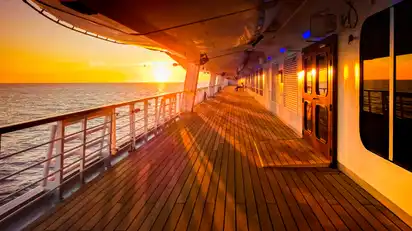 Deckpromenade eines Kreuzfahrtschiffes im Sonnenuntergang auf hoher See.