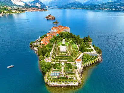 Luftaufnahme der Isola Bella im Lago Maggiore, zeigt den Palazzo Borromeo und den umliegenden Garten auf der Insel, umgeben von Wasser und den benachbarten Borromäischen Inseln.