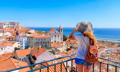 Touristin genießt die Aussicht auf die Altstadt von Lissabon und das Meer im Hintergrund.