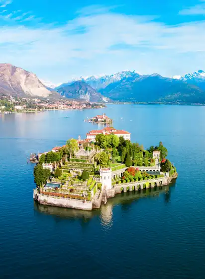Insel mit Schloss und Garten in einem See vor Bergkulisse
