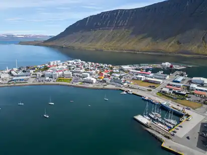 Küstenstadt mit Hafen, umgeben von Bergen und Meer.