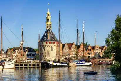 Hafenansicht mit historischen Gebäuden und Segelbooten bei sonnigem Wetter.
