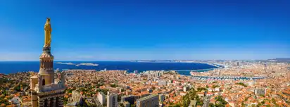 Blick über Marseille mit Notre-Dame de la Garde und Mittelmeer im Hintergrund.