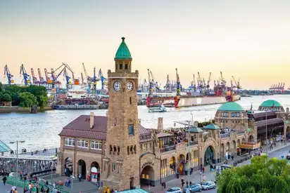 Hafenpanorama mit historischem Gebäude und Kränen bei Sonnenuntergang in Hamburg.