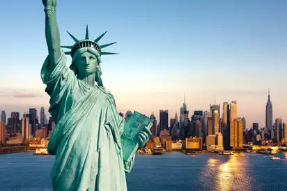 Freiheitsstatue vor der Skyline von Manhattan in New York City bei Sonnenuntergang.