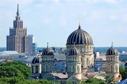 Orthodoxe Kirche mit Kuppeln und ein Hochhaus im Hintergrund in einer Stadtlandschaft.