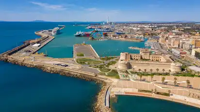 Luftaufnahme eines Hafens mit historischem Fort und umliegender Stadt am Meer.