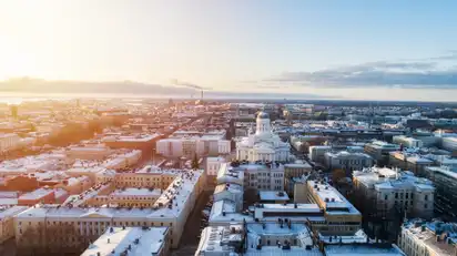 Luftaufnahme einer Stadt bei Sonnenaufgang mit Gebäuden im Schnee.