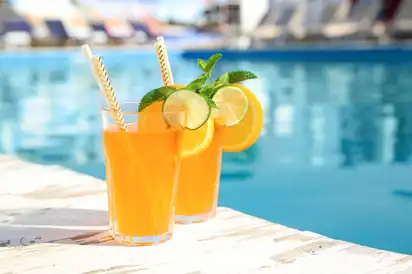 Zwei Gläser Eistee mit Limettenscheiben am Pool.