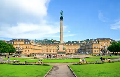 Schlossplatz in Stuttgart mit Jubiläumssäule und Menschen im Grünen.