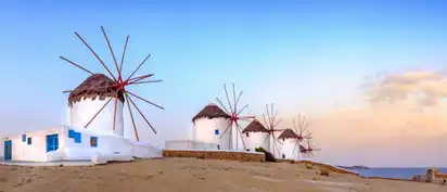 Weiße Windmühlen auf einem Hügel bei Sonnenuntergang.