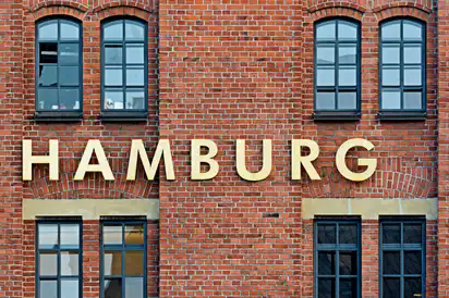 Backsteinfassade mit großen goldenen Buchstaben, die "Hamburg" buchstabieren, davor mehrere Fenster im historischen Stil der Speicherstadt in Hamburg, Deutschland.