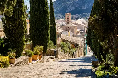 Malerische Treppe in mediterranem Dorf mit Zypressen und Kirche im Hintergrund