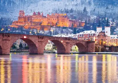 Alte Brücke und Heidelberger Schloss im Winter bei Dämmerung.