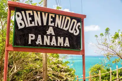 Willkommensschild in Panama vor tropischer Landschaft und Meer.