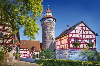 Fachwerkhäuser und ein mittelalterlicher Turm bei sonnigem Himmel.