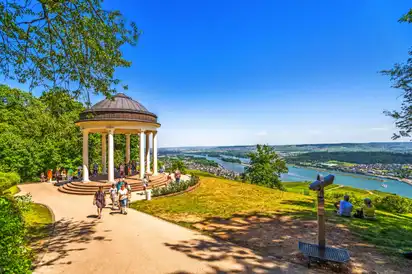 Pavillon mit Menschen auf einem Hügel, im Hintergrund ein Fluss und Landschaft.