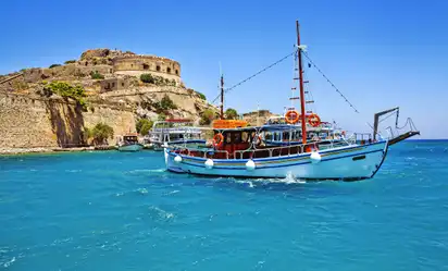 Boot auf blauem Wasser vor einer alten Festung bei Sonnenschein