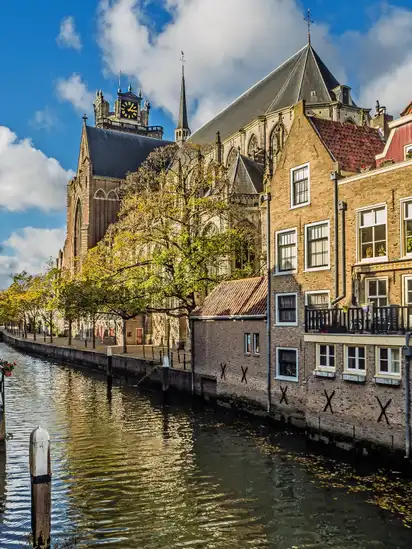 Kirche und traditionelle Gebäude an einem Kanal bei sonnigem Wetter.