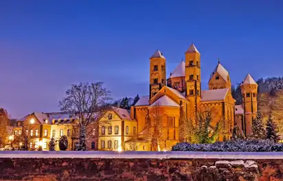 Abtei Maria Laach im Winter bei Abenddämmerung beleuchtet.