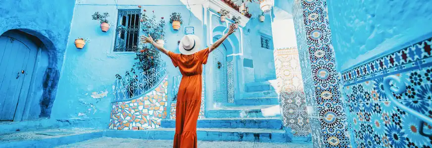 Frau mit rotem Kleid besucht die blaue Stadt Chefchaouen in Marokko