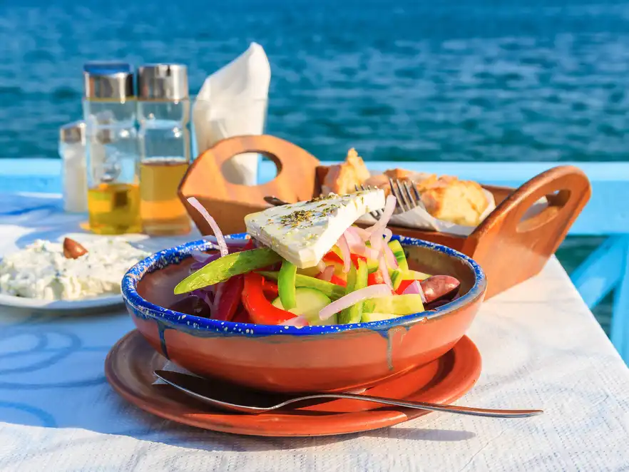 Griechischer Salat in der griechischen Taverne mit blauem Meerwasser im Hintergrund
